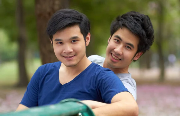 Užívají si svobodu být sami sebou. Roztomilý mladý gayové asijské pár usměvavý spolu zatímco sedí v parku. — Stock fotografie