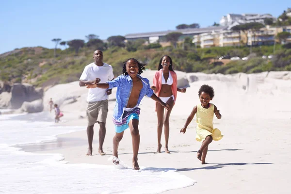 Sto vincendo la gara. Una felice giovane famiglia africana che corre energicamente lungo la spiaggia. — Foto Stock