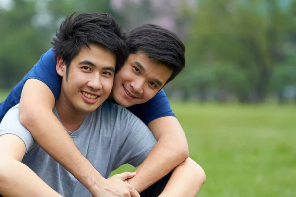 Leva och älska tillsammans. Söta unga homosexuella asiatiska par ler tillsammans medan de sitter i parken. — Stockfoto