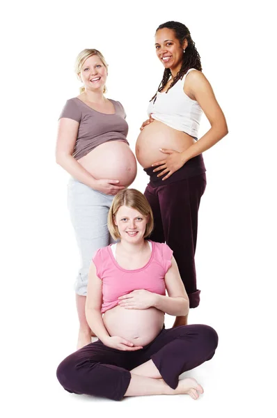 Te ves bellamente embarazada. Embarazadas amigas mostrando sus barrigas juntas mientras están aisladas en blanco. — Foto de Stock