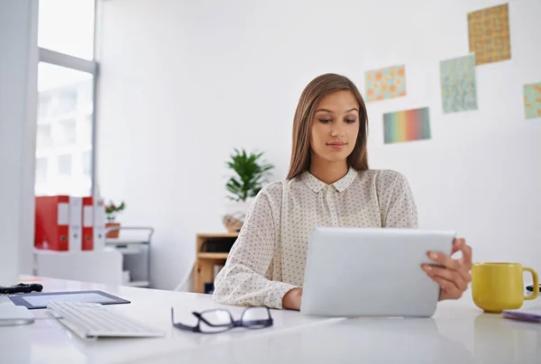 A chave para o sucesso é o trabalho árduo e a determinação. Tiro de uma jovem mulher usando seu tablet digital no escritório. — Fotografia de Stock