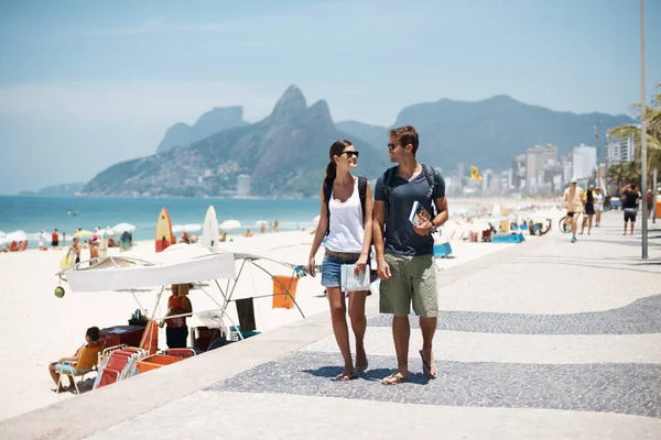 Godendo la spiaggia con un freind. Colpo ritagliato di una giovane coppia che cammina lungo una spiaggia trafficata. — Foto Stock