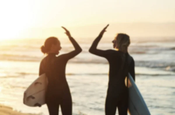 Дай пять и высокие приливы. Снимок сзади молодой пары, которая сцепилась за высокую пятерку во время серфинга на пляже. — стоковое фото
