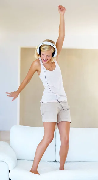 Dansen op het geluid. Een jonge vrouw danst rond tijdens het luisteren naar liedjes op haar hoofdtelefoon. — Stockfoto