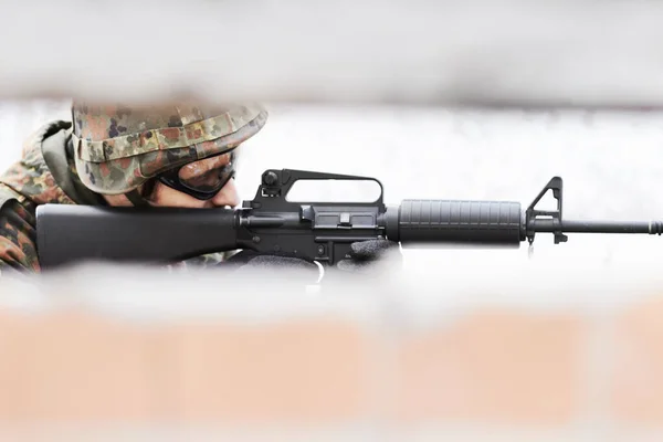 Sharp shooter. Profile of a soldier aiming a gun with a slot in the foreground.