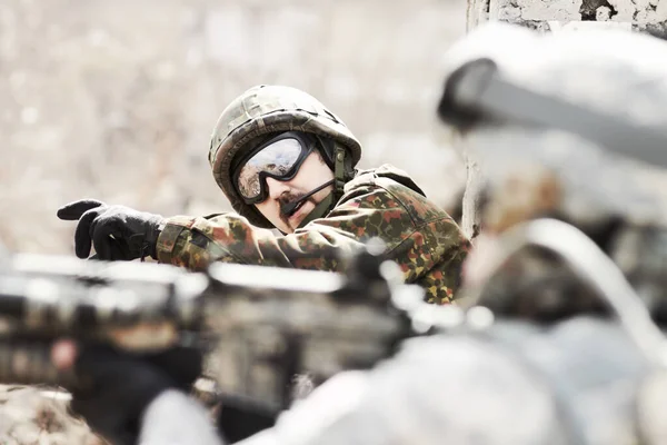 Leidt zijn peloton. Profiel van een commandant die bevelen geeft aan zijn soldaten terwijl ze plat op de grond liggen met geweren in de hand. — Stockfoto