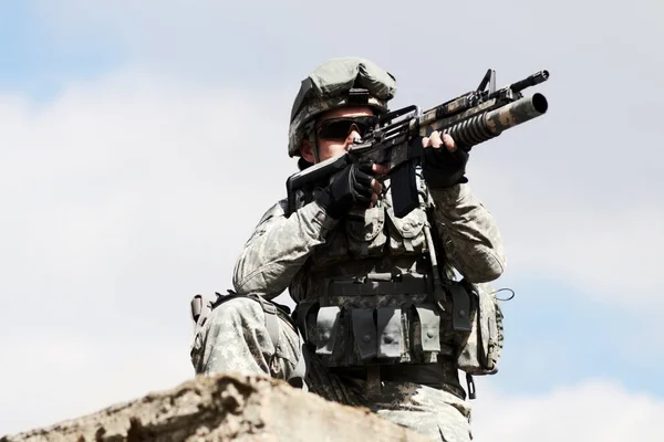 Keeping a watch out. Low angel view of a sniper crouched down on a roof of a building against a sky background.