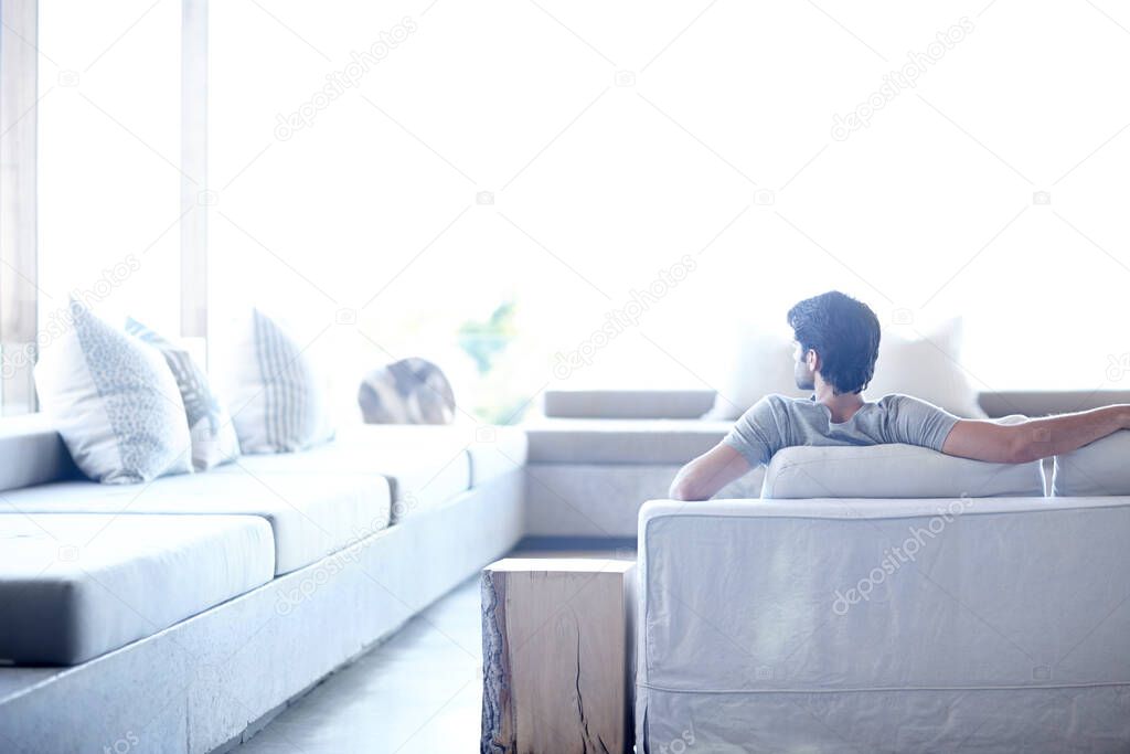 Enjoying the luxury of home. Back view of a man sitting in his living room.