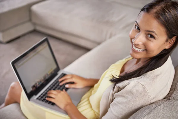 Sieć na kanapie. Portret atrakcyjnej młodej kobiety korzystającej z laptopa podczas siedzenia na kanapie. — Zdjęcie stockowe