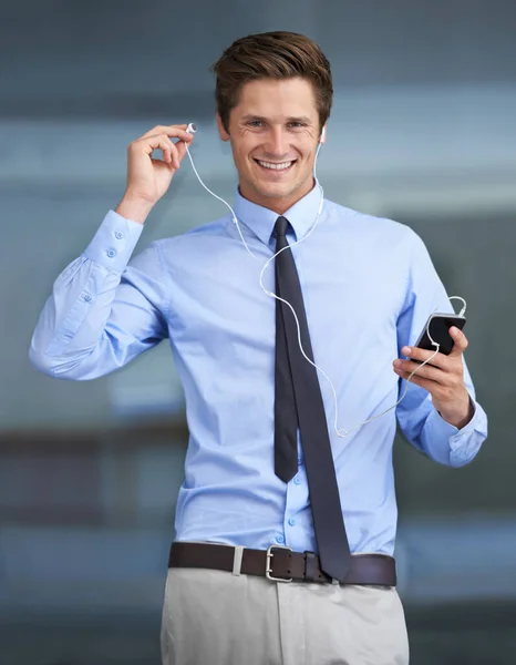 La música me pone de humor para trabajar. Retrato de un joven hombre de negocios guapo usando su teléfono inteligente como reproductor de mp3. —  Fotos de Stock