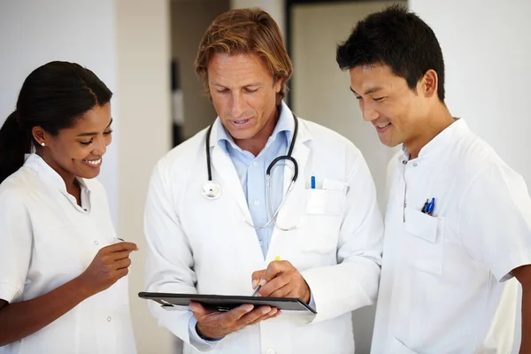 Este diagnóstico é tão fascinante. Tiro de três médicos olhando para um tablet digital. — Fotografia de Stock
