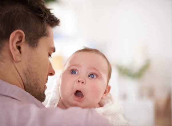 É um pai incrível. Um bebê bonito menina olhando sobre seus pais ombro como ele a segura. — Fotografia de Stock