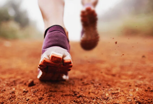 Rompiendo el rastro. Primer plano de una mujer corriendo por un sendero en una mañana brumosa. —  Fotos de Stock