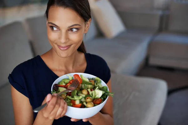 Metiéndose en algo saludable. Vista superior de una hermosa joven disfrutando de una ensalada saludable en su casa. — Foto de Stock