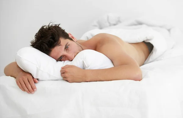 À procura de um abraço. Retrato de um jovem sonolento deitado confortavelmente na cama. — Fotografia de Stock