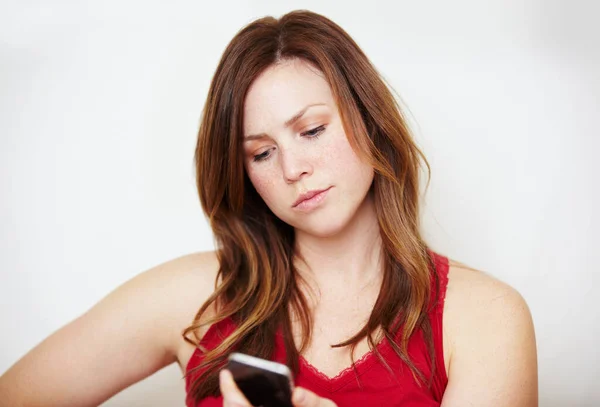 Δεν μπορεί να είναι αλήθεια... μια ενοχλημένη νεαρή γυναίκα να κοιτάει το κινητό της.. — Φωτογραφία Αρχείου