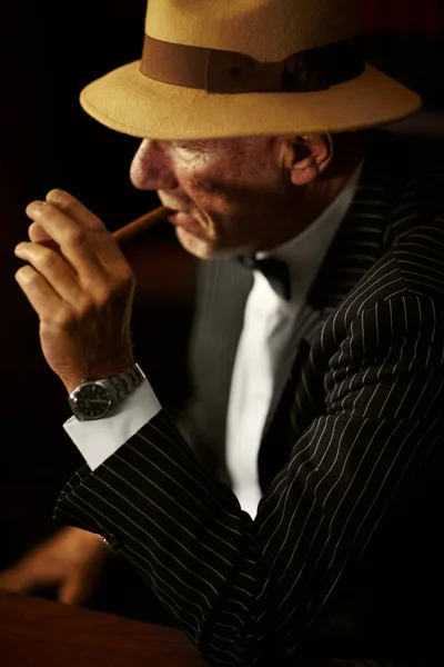Iluminación. Envejecido jefe de la mafia con un sombrero y mirando en serio mientras enciende un cigarrillo. —  Fotos de Stock