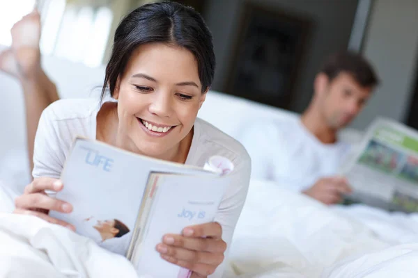 Чем больше ты читаешь, тем больше знаешь. Снимок красивой женщины, лежащей в постели и читающей журнал. — стоковое фото