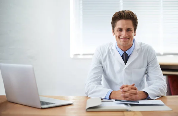 Il a confiance en ses capacités médicales. Portrait d'un médecin souriant assis à son bureau. — Photo