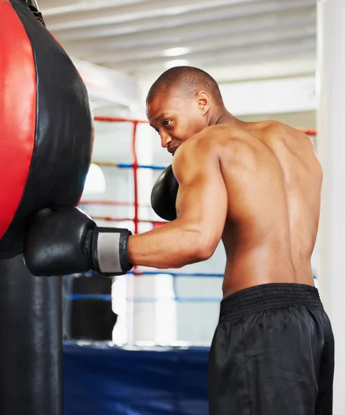 Refining his technique. An african american boxer practicing with a punching ball. — Stock Photo, Image