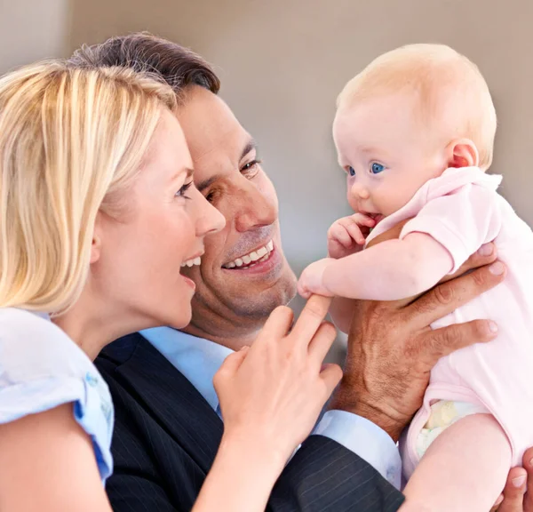 Kijk naar haar mooie blauwe ogen. Jonge moeder en vader giechelen met hun baby. — Stockfoto