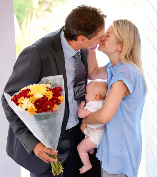 Deze zijn voor jou, schoonheid. Jonge vader brengt bloemen mee naar huis naar zijn mooie familie. — Stockfoto