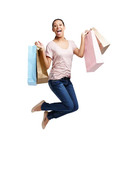 Betalningsdag. Skott av en attraktiv ung kvinna som håller i shoppingväskor och hoppar i luften isolerad på vit. — Stockfoto