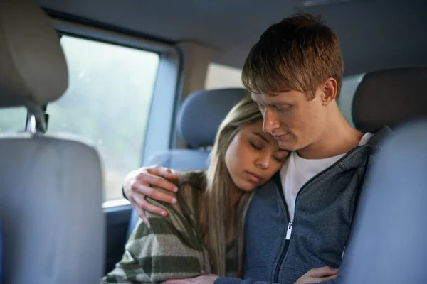 Not long now. Shot of a tired young couple sitting together in the back seat of a car. Stock Photo