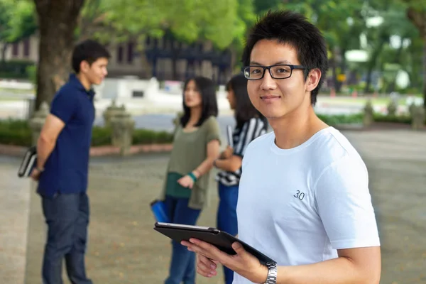 Wykorzystując nowoczesną technologię do nauki do egzaminów końcowych. Portret przystojnego młodego studenta pracującego na tablecie cyfrowym na zewnątrz. — Zdjęcie stockowe