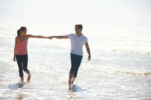 Ты мой один из шести миллиардов. Снимок молодой пары, держащейся за руки во время прогулки по пляжу. — стоковое фото