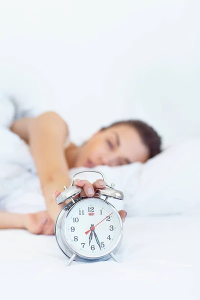 Noch 5 Minuten.... Aufnahme einer verschlafenen jungen Frau, die nach ihrem Wecker greift. — Stockfoto