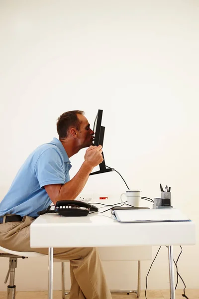 Gracias. Gracias. Un hombre de mediana edad besa con entusiasmo la pantalla de su computadora mientras está sentado en su escritorio. — Foto de Stock