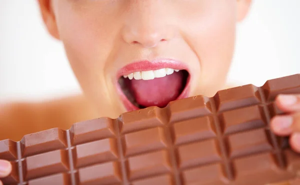 Entrando per un morso.... Vista ritagliata di una giovane donna che morde una grande lastra di cioccolato. — Foto Stock