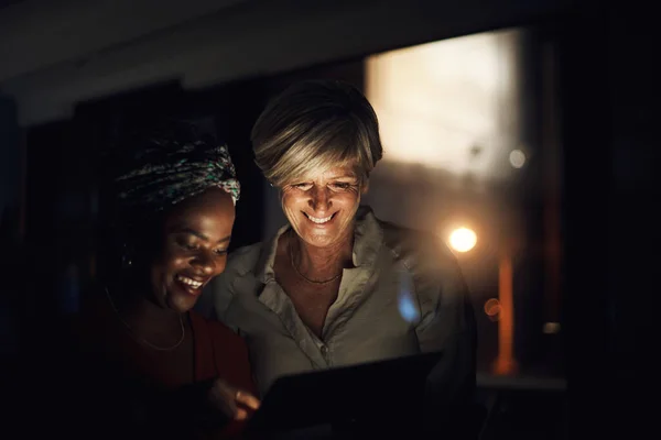 Was ist unser nächster großer Schritt? Aufnahme zweier Geschäftsfrauen, die nachts gemeinsam ein digitales Tablet im Büro benutzen. — Stockfoto