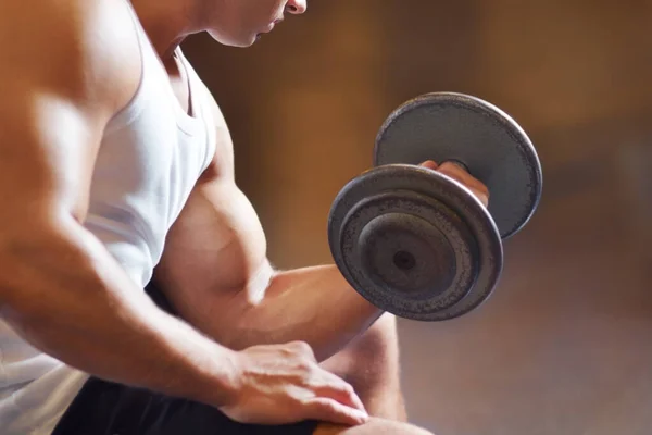 Trabajando sus bíceps. Recorte de un joven musculoso haciendo ejercicio en el gimnasio. — Foto de Stock