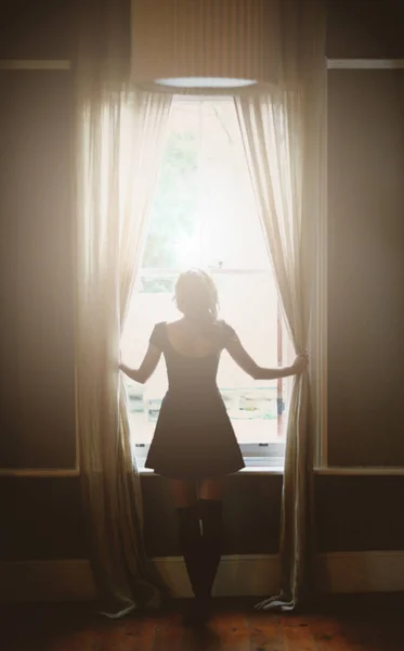 Its going to be a beautiful day.... Full length rear view of a young woman looking out the window. — Stock Photo, Image