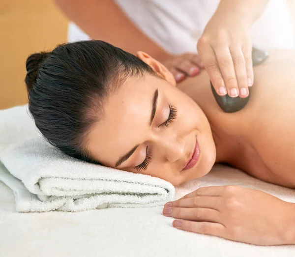 Concedersi un massaggio tanto necessario. Colpo ritagliato di una giovane donna attraente che gode di un massaggio con pietre calde in una spa. — Foto Stock