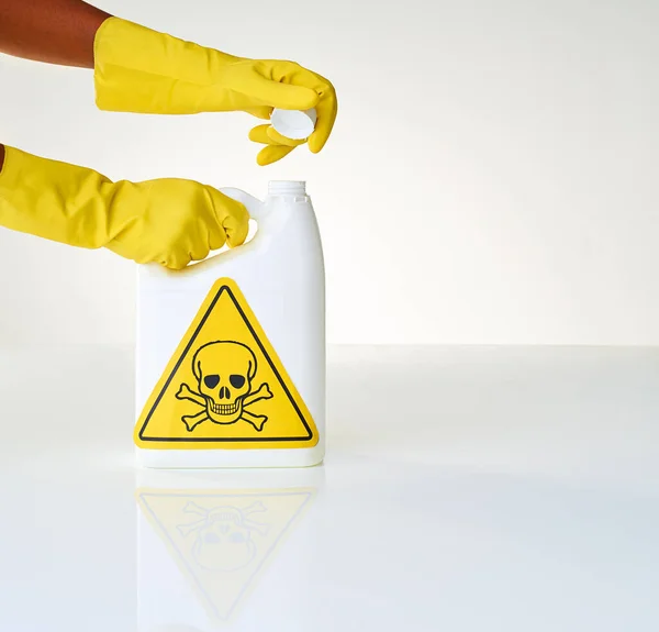 Vorsicht - mit Vorsicht behandeln. Schnappschuss einer Person beim Öffnen einer Flasche giftiger Flüssigkeit vor grauem Hintergrund. — Stockfoto