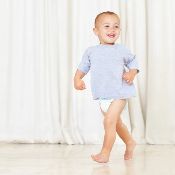 Stottern seine Sachen. In voller Länge Aufnahme eines niedlichen kleinen Jungen, der in Windel und T-Shirt durch das Haus läuft. — Stockfoto