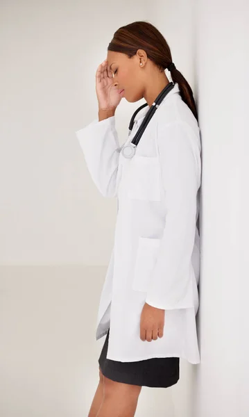 Potilaan menetys. Stressaantunut etninen nainen lääkäri nojaa seinää vasten. — kuvapankkivalokuva