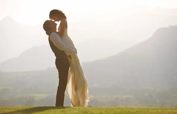 Boda escénica. Un novio levantando a su novia en el aire. — Foto de Stock