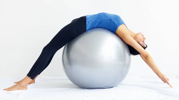 Dem totalen Wohlbefinden gewidmet. Junge Frau in weißer Isolation über einen Schweizer Ball gestreckt. — Stockfoto