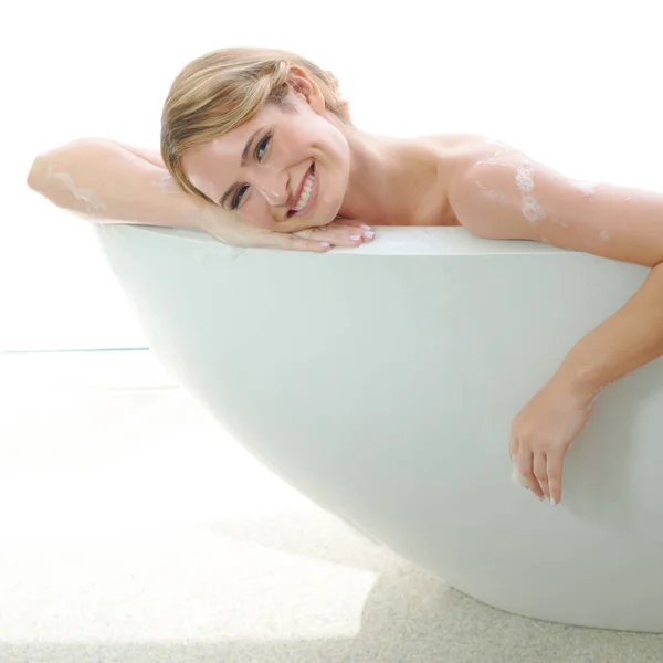 Le gusta mimarse a sí misma. Una hermosa joven sonriente mientras disfruta de un lujoso baño. — Foto de Stock