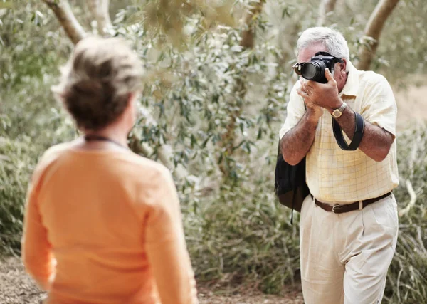 Du siehst schön aus. Ein älterer Mann fotografiert seine Frau beim Spaziergang im Urlaub. — Stockfoto