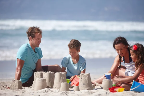 Costruire castelli di sabbia uno dei piaceri della vita semplici. Girato di una famiglia felice costruzione castelli di sabbia insieme in spiaggia. — Foto Stock