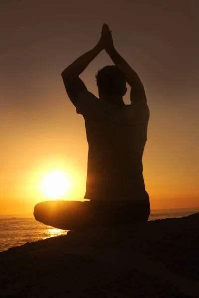 Poczucie jedności z wszechświatem. Sylwetka mężczyzny przed zachodem słońca z podniesionymi ramionami w pozycji do jogi.. — Zdjęcie stockowe