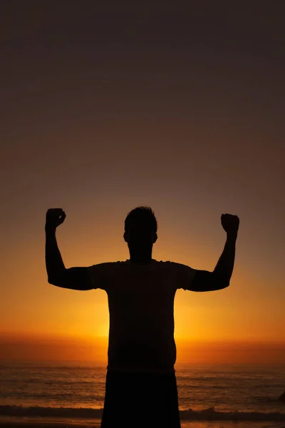 Encontrando el poder dentro. Silueta de un hombre de pie con los brazos levantados victoriosamente contra el atardecer. —  Fotos de Stock