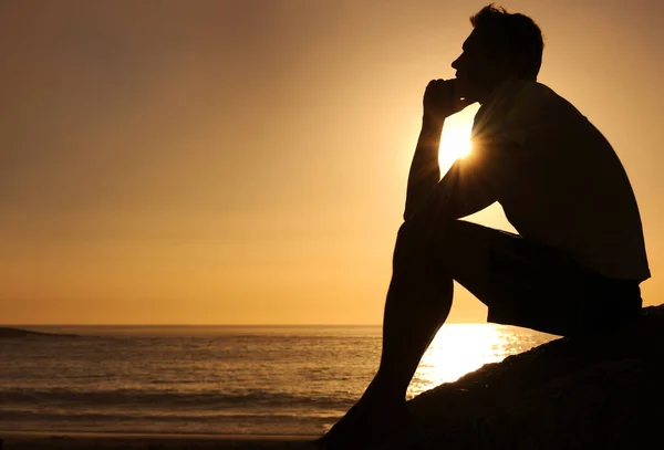 Buscando respuestas de vida. Silueta de un hombre reflexivo sentado junto al océano - copyspace. —  Fotos de Stock