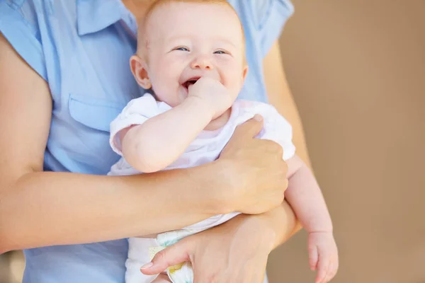 Klein meisje dat gelukkig lacht. Een schattige baby meisje lachen terwijl wordt vastgehouden door haar moeder. — Stockfoto