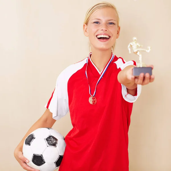 Könnyen nyerhet. Egy fiatal nő portréja foci egyenruhában, trófeát és focilabdát tartva.. — Stock Fotó